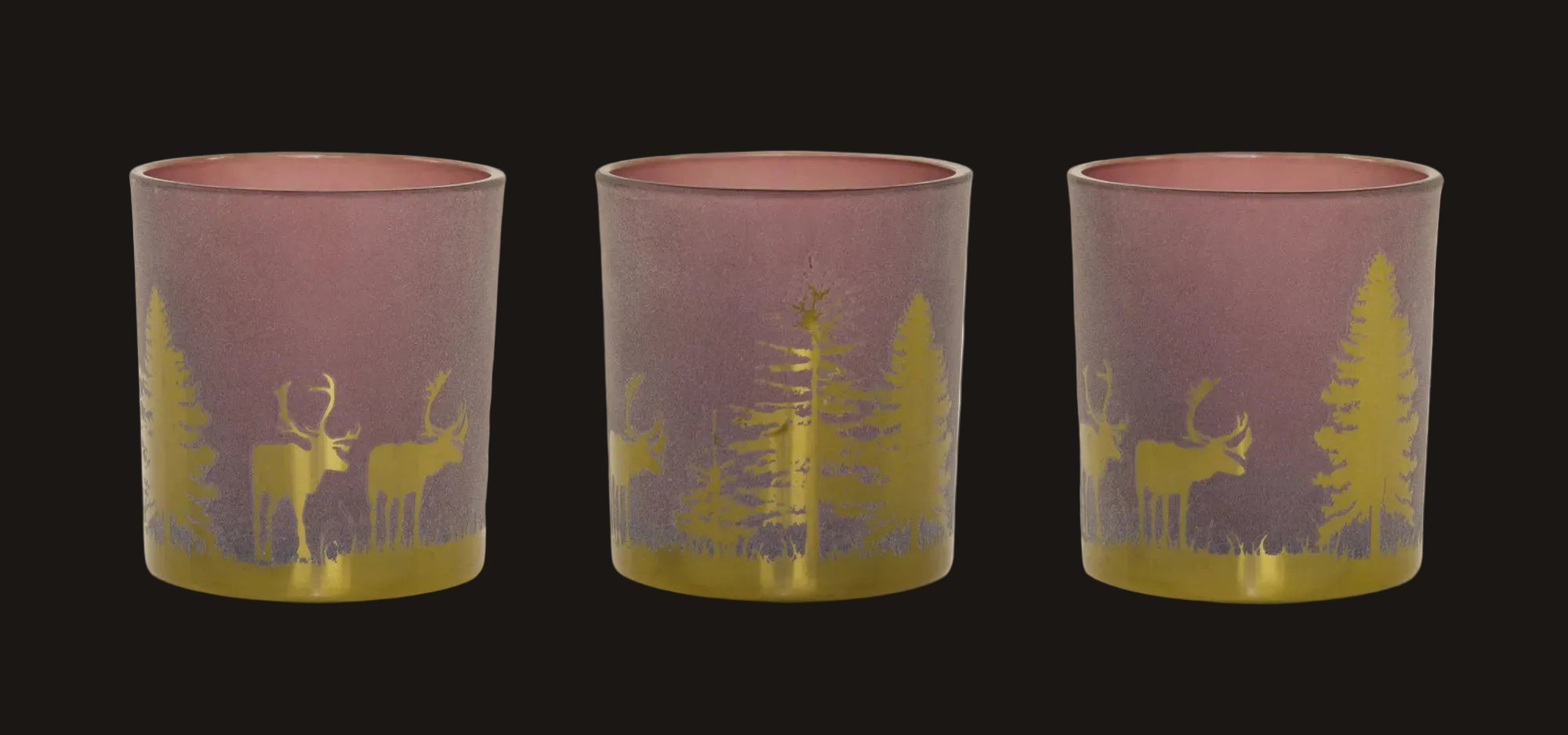 Three pink and gold candle holders with deer and tree design on a white background